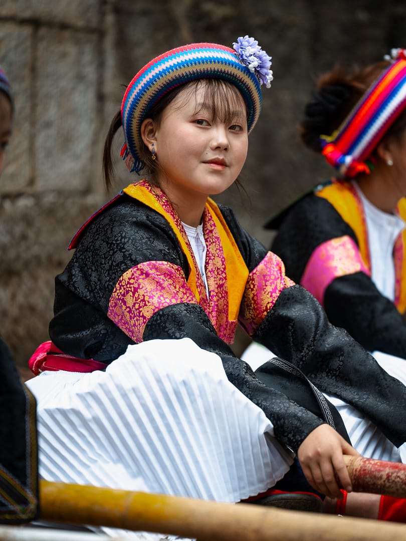A young woman wears an elaborately embroidered headscarf and costume for a local festival.